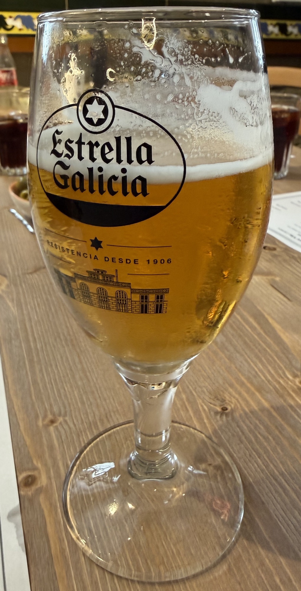 Pahar de bere Estrella Galicia pe masă de lemn
